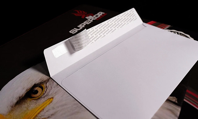 Open white 120gsm peel and seal long edge wallet flap custom printed envelope by TradePrintingUK.com, displaying visible adhesive strip, blank interior for documents, and secure closure mechanism on dark background with branding elements.