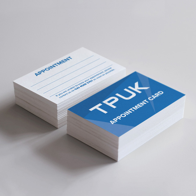 Stacks of custom printed appointment cards by TradePrintingUK.com on a light gray background, featuring white cards with blue APPOINTMENT headings and blank fields for client details plus cancellation instructions with London phone number, next to blue cards with APPOINTMENT CARD branding, designed for hair and beauty salons, dental and health clinics, or service businesses.