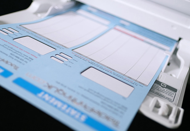Custom printed Sage accounting statement on 100gsm Bond by TradePrintingUK.com loaded in a laser printer tray. The personalised business form demonstrates jam-free paper compatibility with light blue header and pink accents, ideal for laser printer office use in the UK.