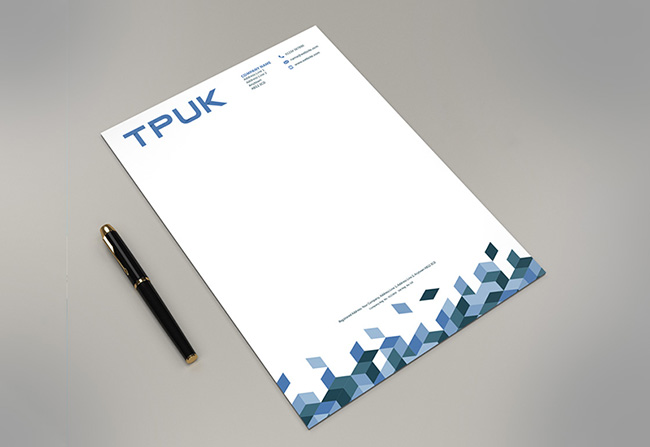 Custom printed TPUK letterhead on 120gsm Bond from TradePrintingUK.com shown with a black fountain pen on grey background. The personalised headed paper features a blue TPUK logo, contact details, and geometric diamond motif in blue tones at the base